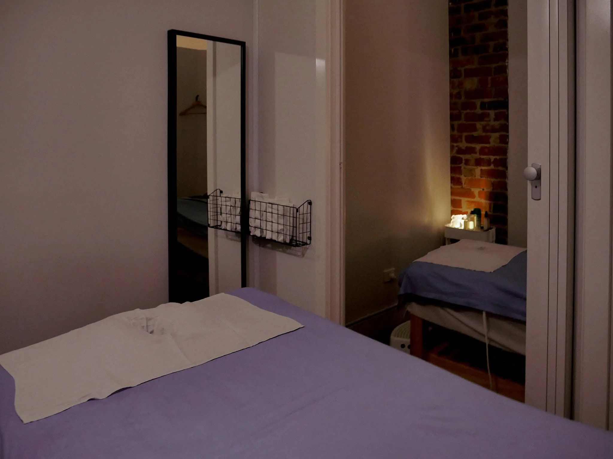 Treatment room with blue massage bed and red hibiscus on patterned cloth