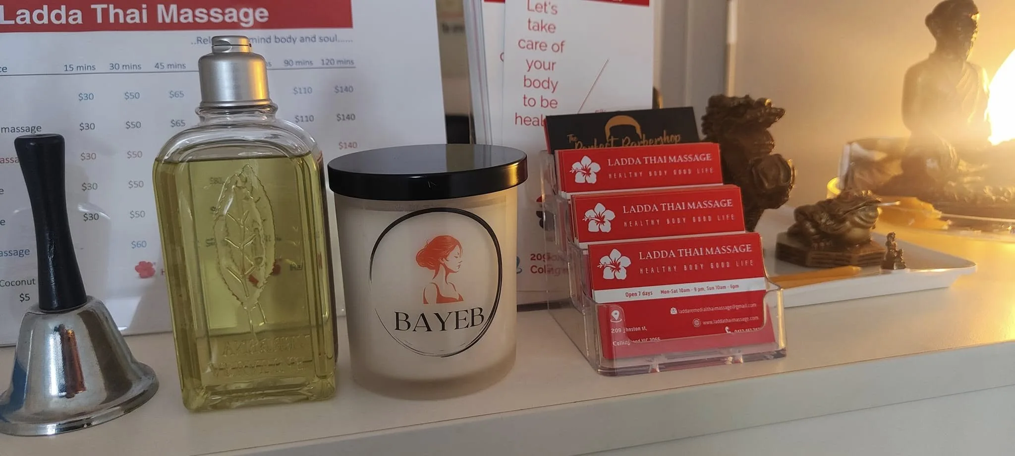 Ladda Thai Massage reception counter with massage oil, BAYEB candle and business cards in warm light